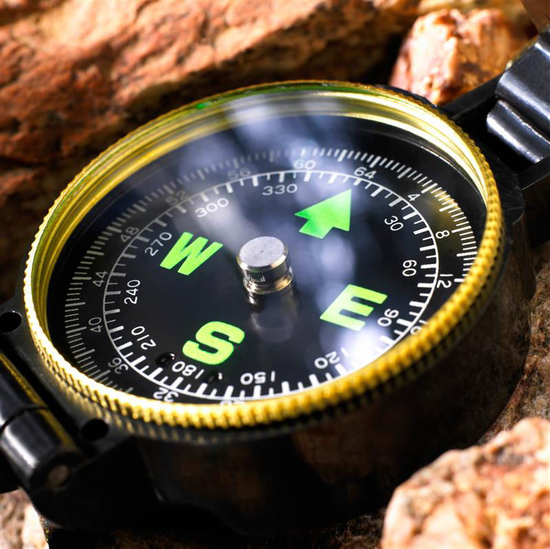 Compass with green directional markers on a rocky surface.
