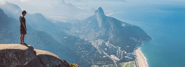 Person standing on a cliff overlooking Rio de Janeiro’s coastline and city